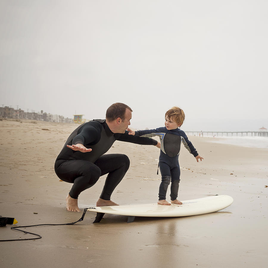 Caucasian father teaching son to surf Photograph by Pacific Images