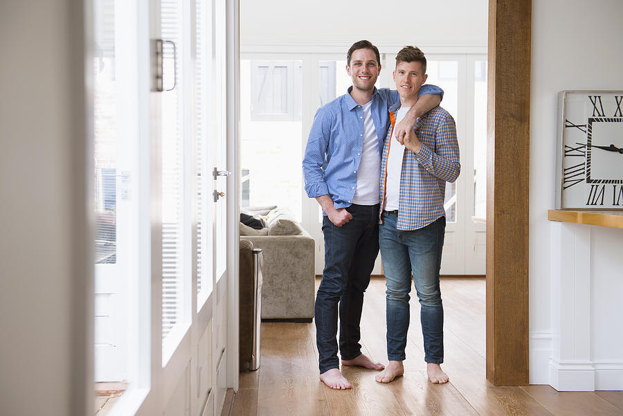 Caucasian gay couple hugging in living room Photograph by Jacobs Stock Photography Ltd