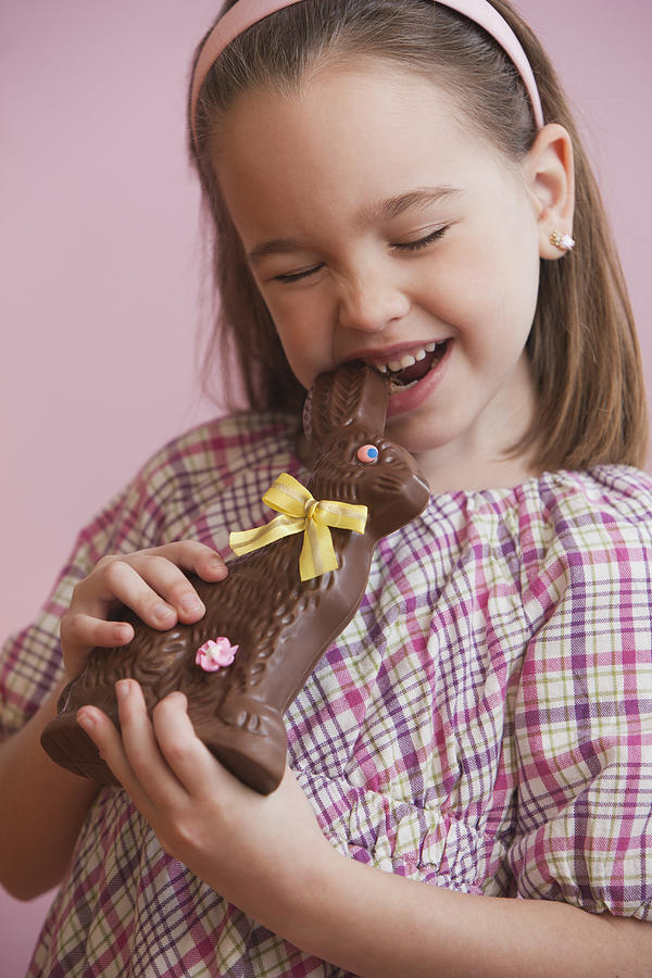 Caucasian girl eating chocolate Easter bunny Photograph by Jose Luis Pelaez Inc