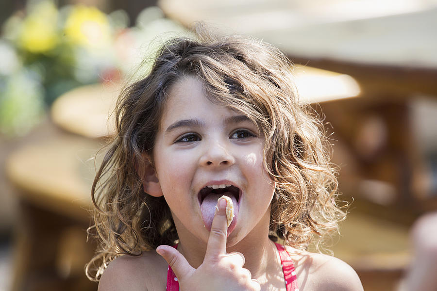 Caucasian girl licking finger outdoors Photograph by Ronnie Kaufman