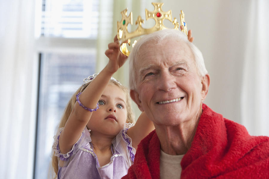 Caucasian girl putting crown on grandfathers head Photograph by Jose Luis Pelaez Inc