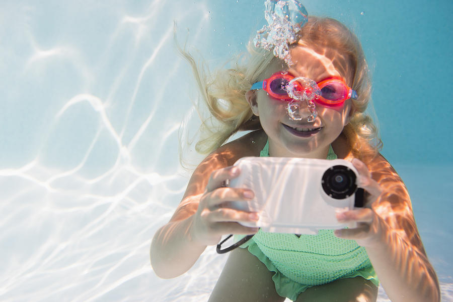 Caucasian girl taking photograph underwater in pool Photograph by JGI/Jamie Grill