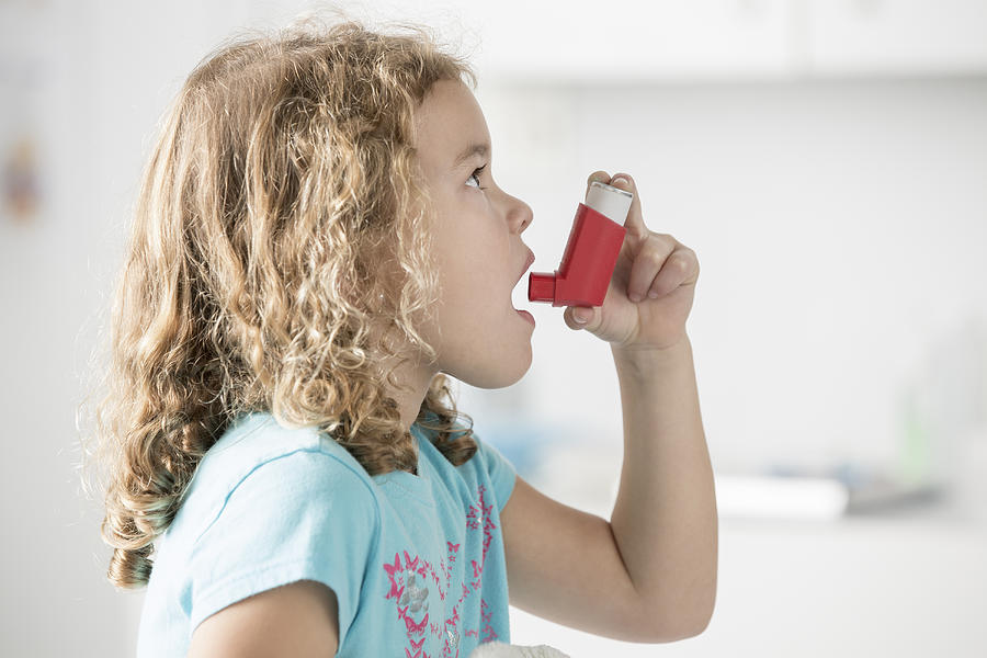 Caucasian girl using inhaler in doctors office Photograph by Terry Vine