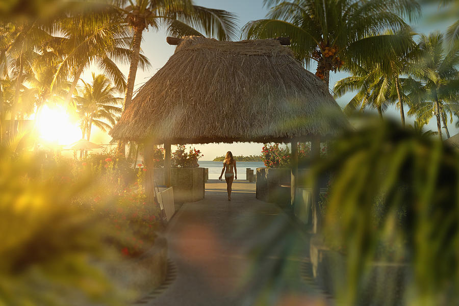 Caucasian girl walking under hut in tropical beach Photograph by Colin Anderson Productions pty ltd