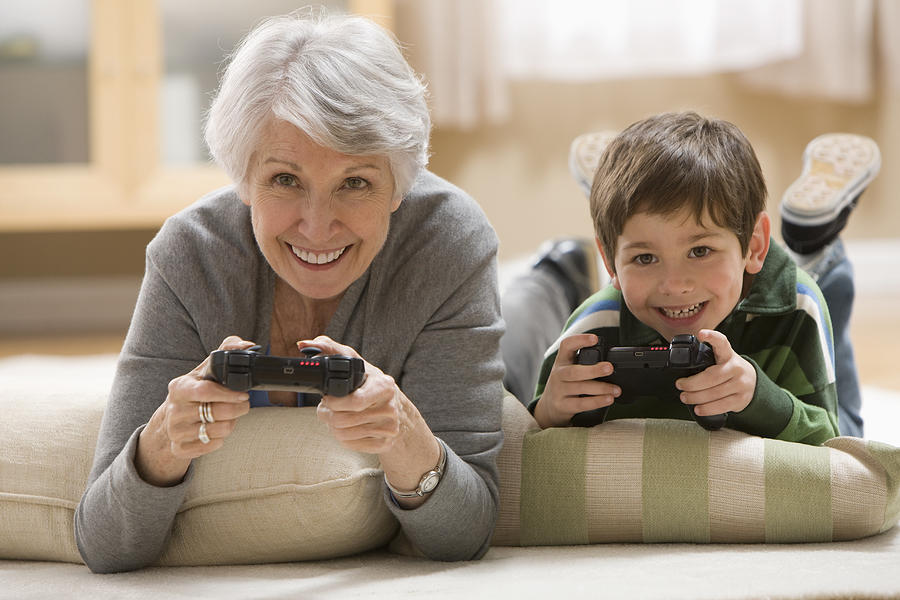Caucasian grandmother and grandson playing video game Photograph by Jose Luis Pelaez Inc