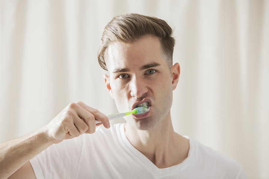 Caucasian man brushing his teeth Photograph by Mike Kemp