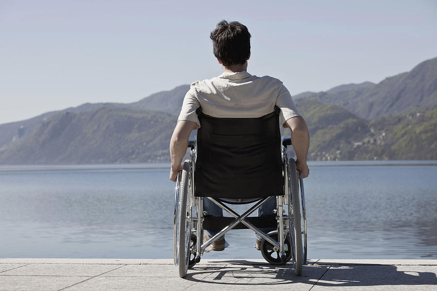 Caucasian man in wheelchair sitting on dock Photograph by Walter Zerla