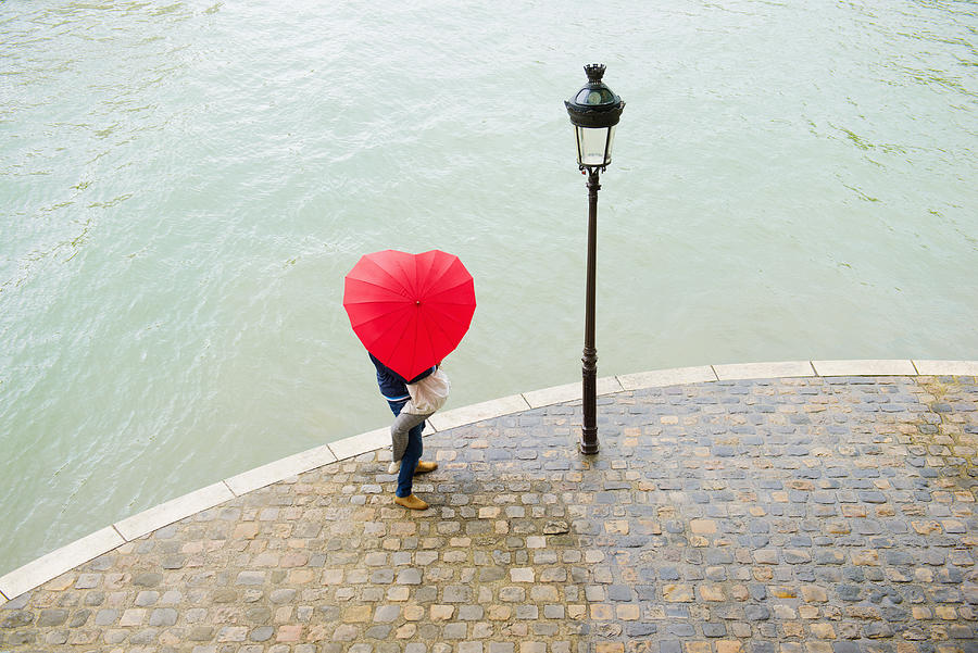 Caucasian man lifting girlfriend under heart shape umbrella Photograph by Jacobs Stock Photography Ltd
