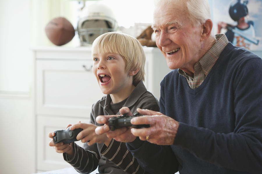 Caucasian man playing video game with grandson Photograph by Jose Luis Pelaez Inc