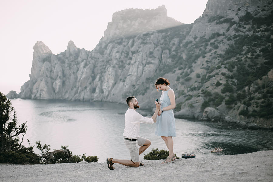 Caucasian man proposing marriage to woman at beach Photograph by Alexey Karamanov