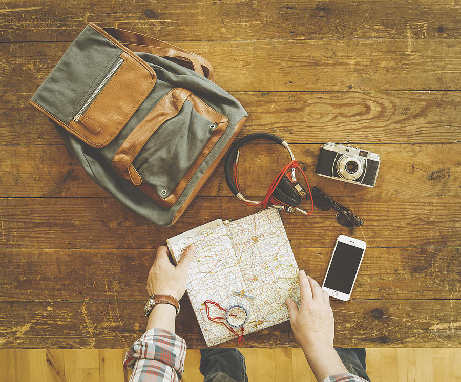 Caucasian man reading map with travel accessories on wooden table Photograph by Jacobs Stock Photography Ltd