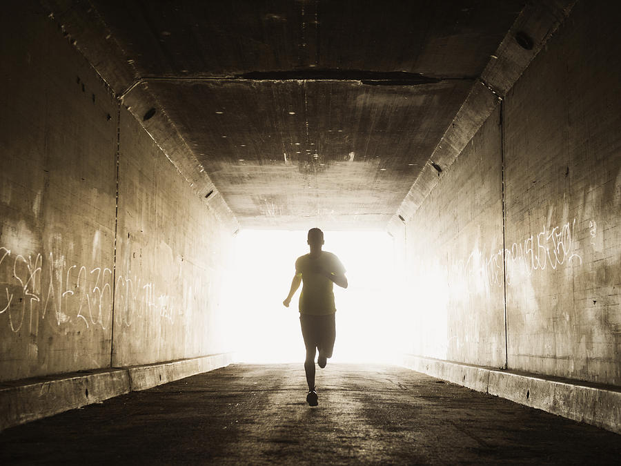 Caucasian man running in urban tunnel Photograph by Erik Isakson