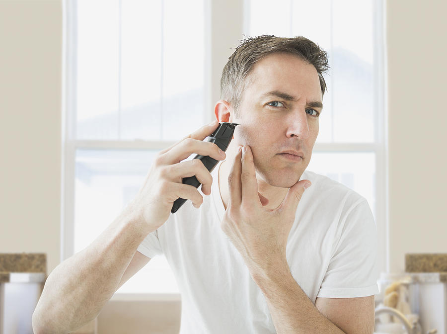 Caucasian man shaving in bathroom Photograph by Mike Kemp