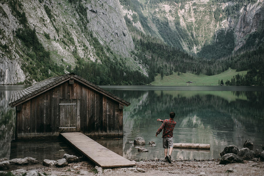 Caucasian man skipping stones in mountain lake Photograph by Alexey Karamanov