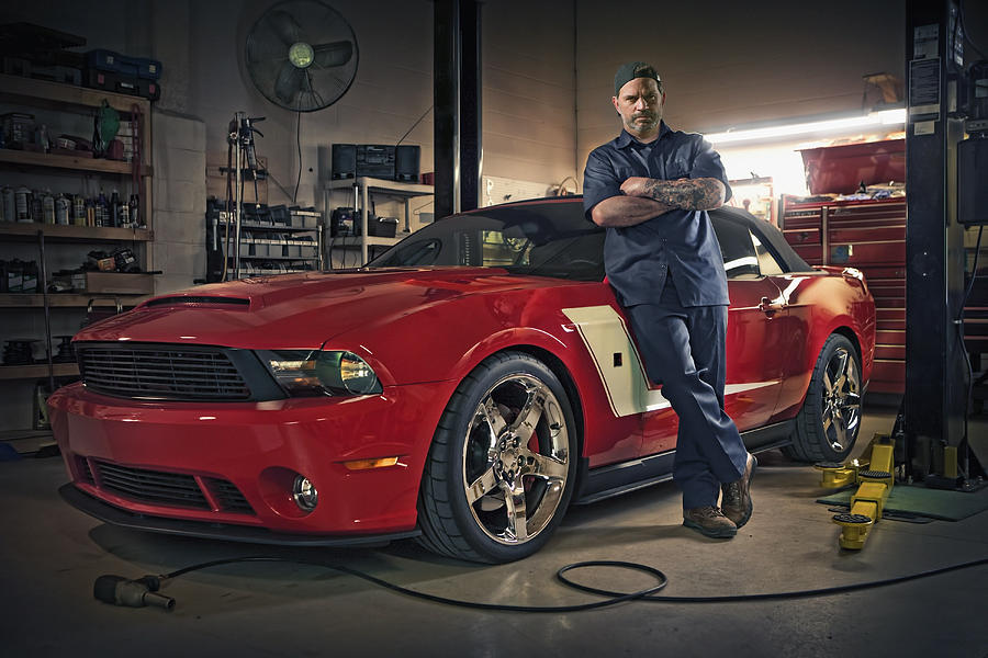 Caucasian mechanic posing on red sports car Photograph by Chris Clor