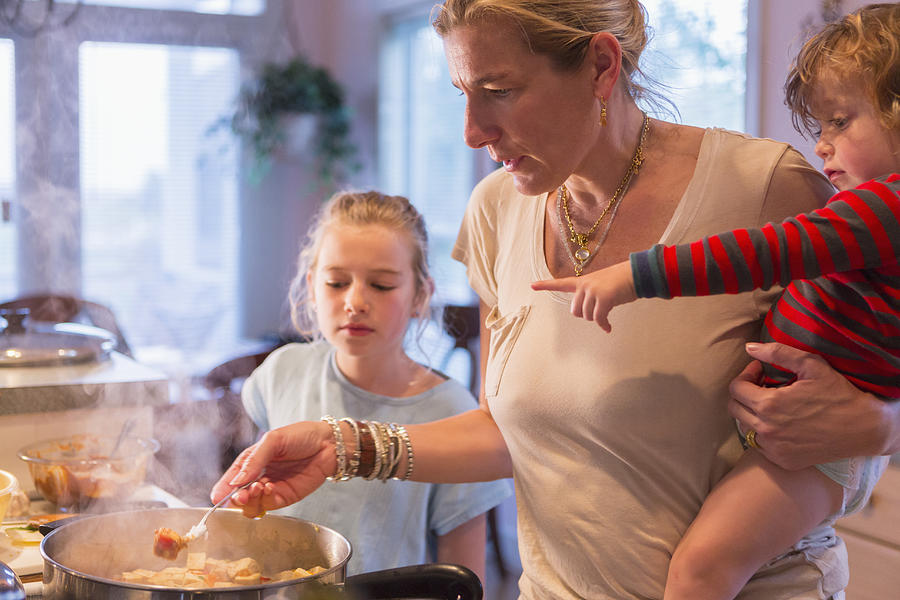 Caucasian mother and children cooking in kitchen Photograph by Marc Romanelli