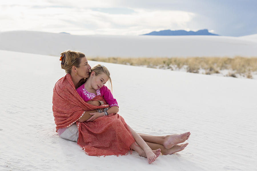 Caucasian mother and daughter wrapped in blanket on sand dune Photograph by Marc Romanelli