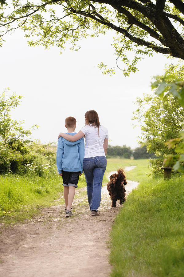 Caucasian mother and son walking dog on dirt path Photograph by Jacobs Stock Photography Ltd