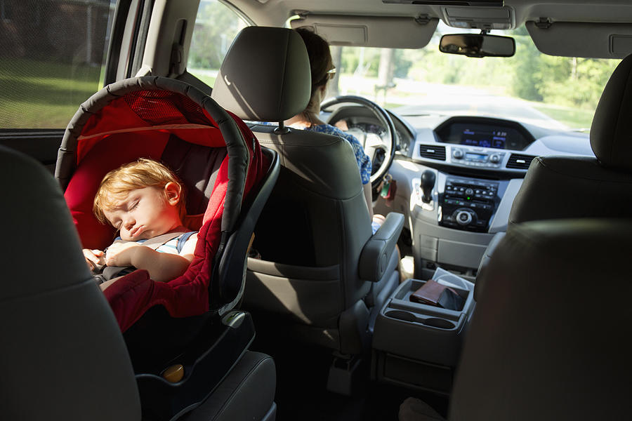 Caucasian mother driving car with baby son in car seat Photograph by Roberto Westbrook