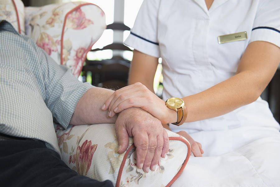 Caucasian nurse measuring pulse of patient in home Photograph by Jacobs Stock Photography Ltd