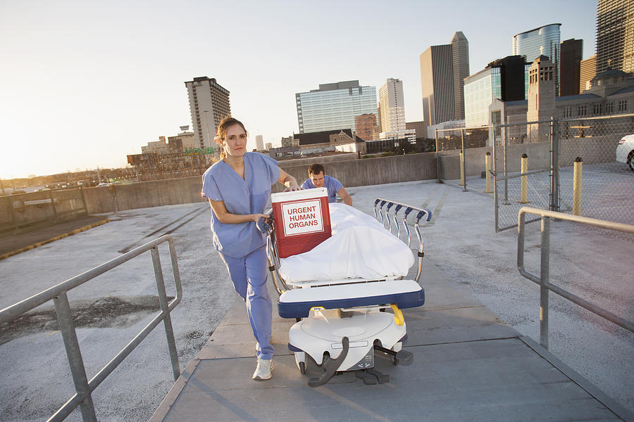 Caucasian nurses rushing organs and patient on rooftop Photograph by ER Productions Limited