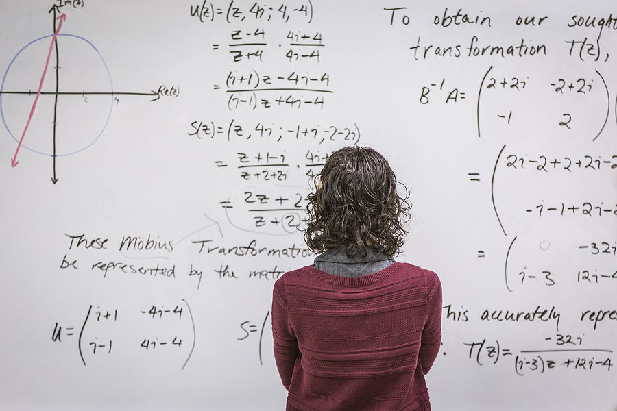Caucasian professor examining equations on whiteboard Photograph by Hill Street Studios