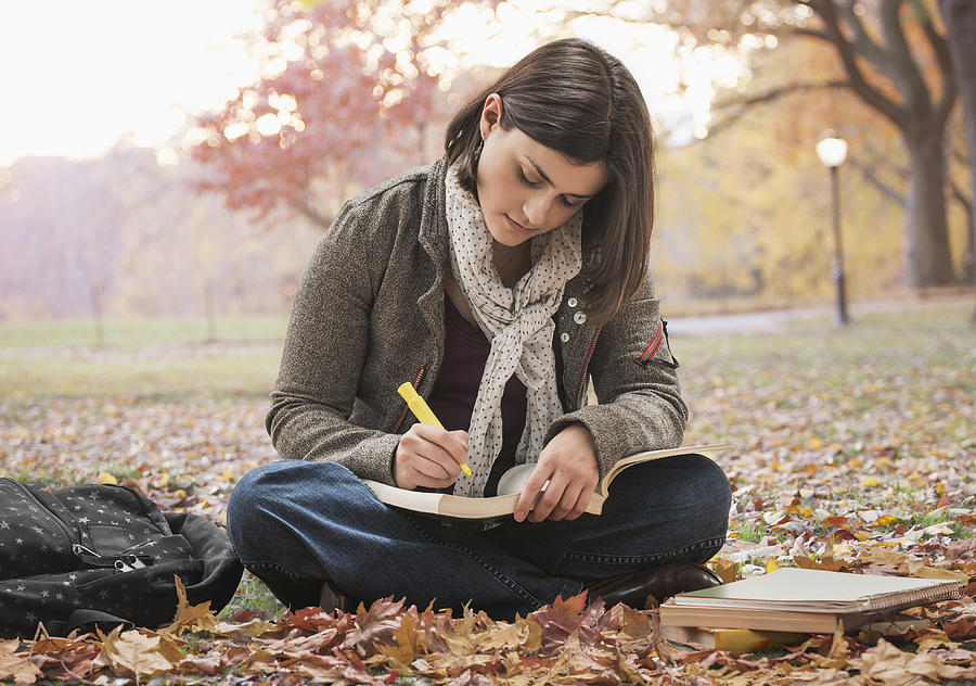 Caucasian student reading in park with autumn leaves Photograph by Jose Luis Pelaez Inc