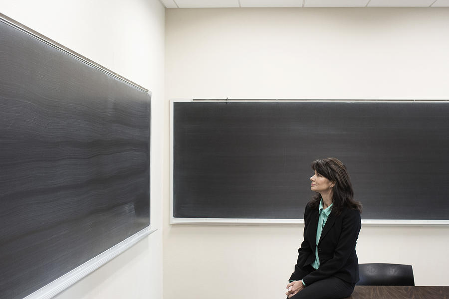 Caucasian teacher sitting in empty classroom Photograph by Hill Street Studios