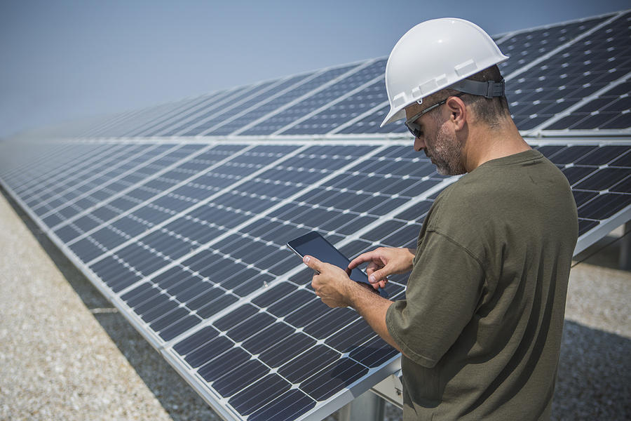Caucasian technician using digital tablet near solar panels Photograph by John Fedele