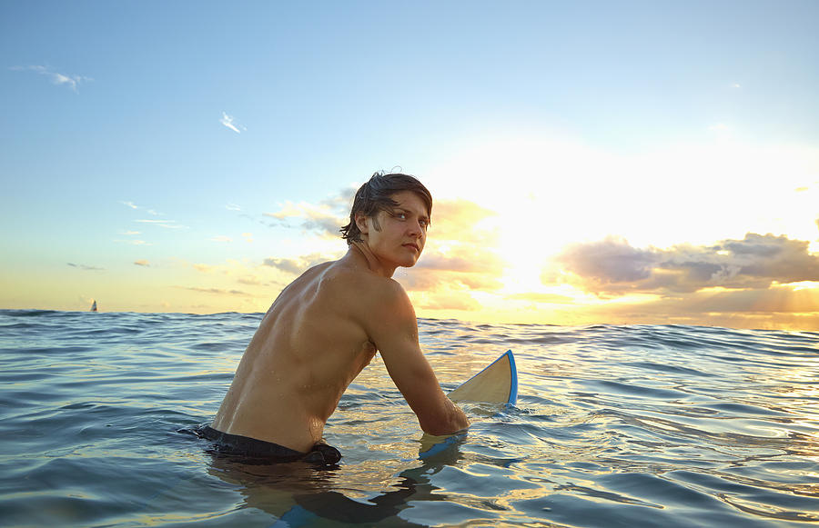 Caucasian teenage boy floating on surfboard in ocean Photograph by Colin Anderson Productions pty ltd