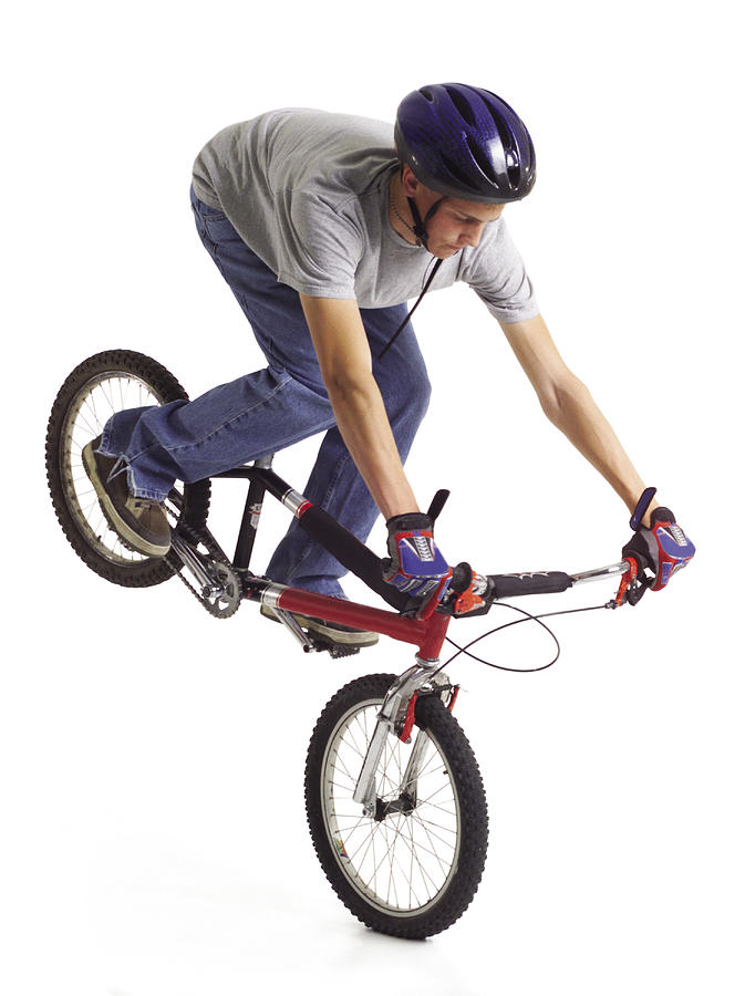 Caucasian Teenage Boy Wears Blue Bike Helmet Doing A Stunt On Red Bike With Rear Tire In The Air Photograph by Photodisc