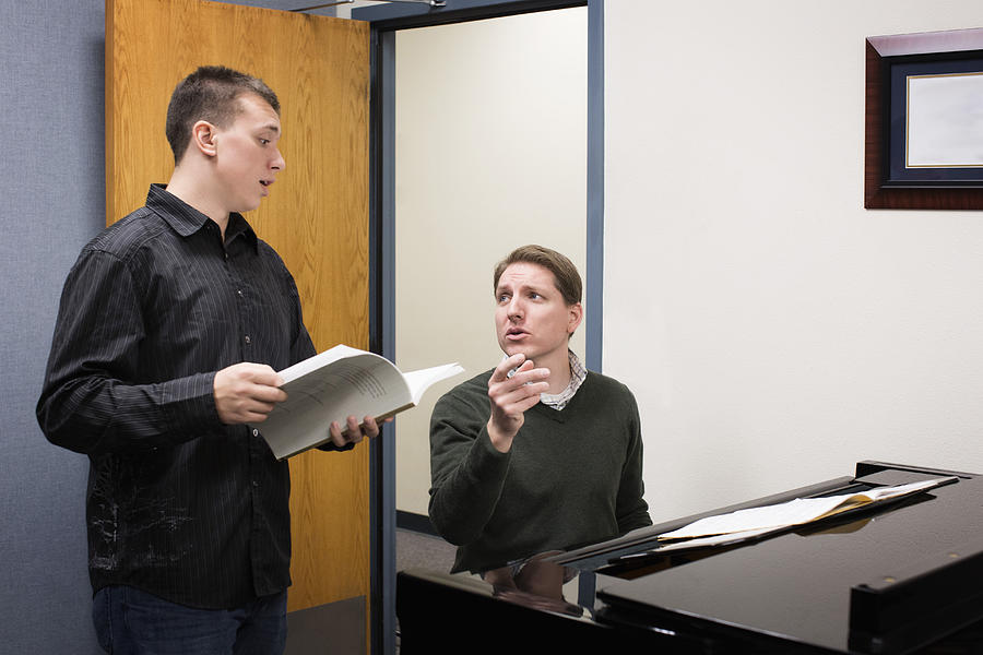 Caucasian vocal teacher and student singing at piano Photograph by Hill Street Studios
