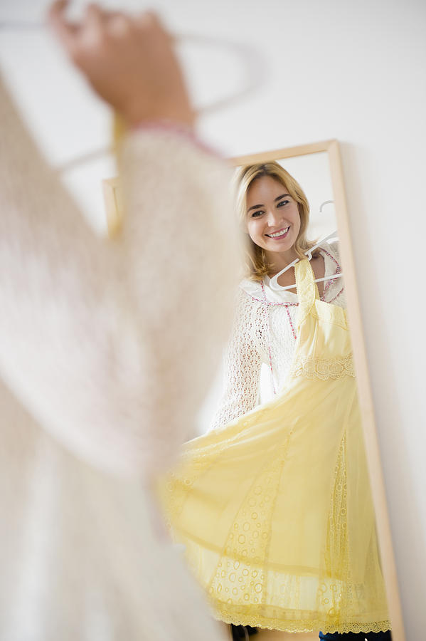 Caucasian woman admiring dress in mirror Photograph by JGI/Jamie Grill
