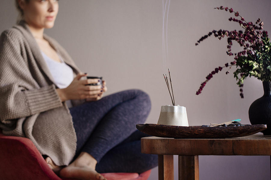 Caucasian woman burning incense in living room Photograph by Lumina Images