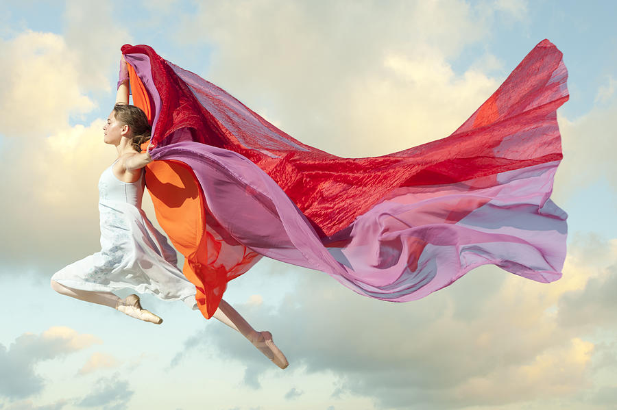Caucasian woman floating through air with scarves Photograph by Pete Saloutos