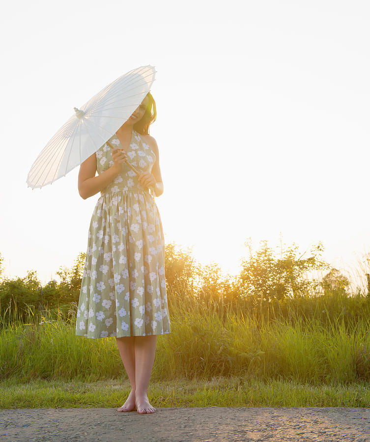 Caucasian woman holding parasol on rural road Photograph by Jacobs Stock Photography Ltd