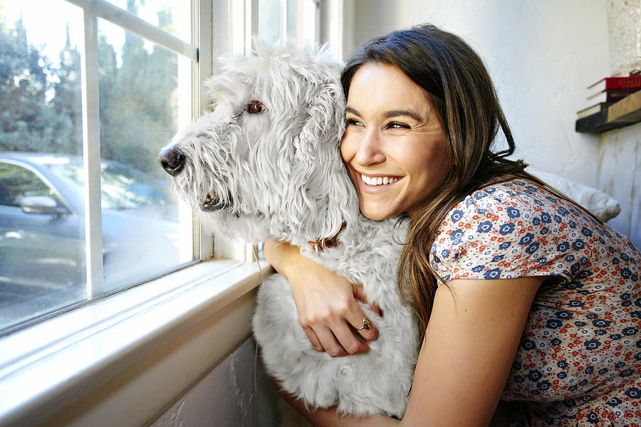Caucasian woman hugging dog at window Photograph by Blend Images - Peathegee Inc