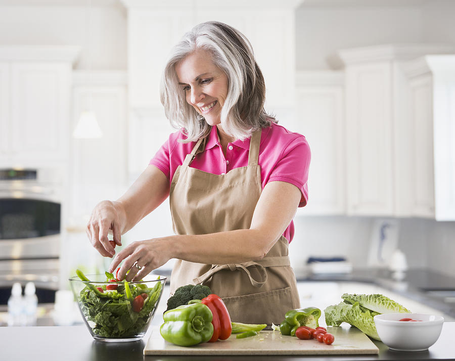 Caucasian woman preparing salad in kitchen Photograph by Mike Kemp