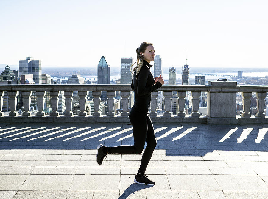Caucasian woman running in city Photograph by Mint Images