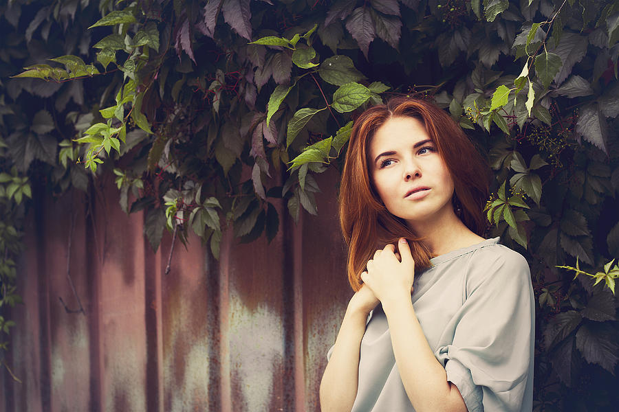 Caucasian woman standing under leaves by fence Photograph by Maxim Chuvashov