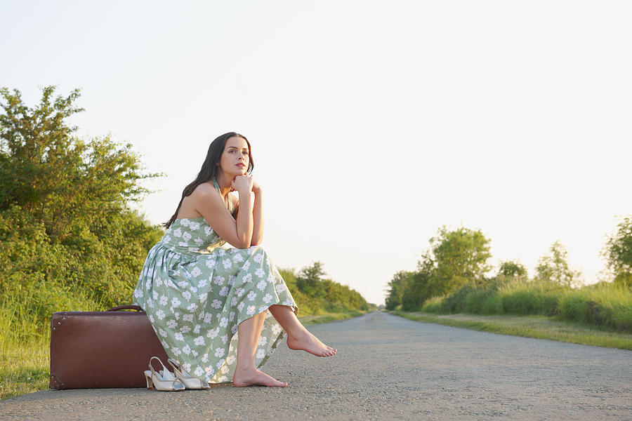 Caucasian woman with suitcase waiting on rural road Photograph by Jacobs Stock Photography Ltd