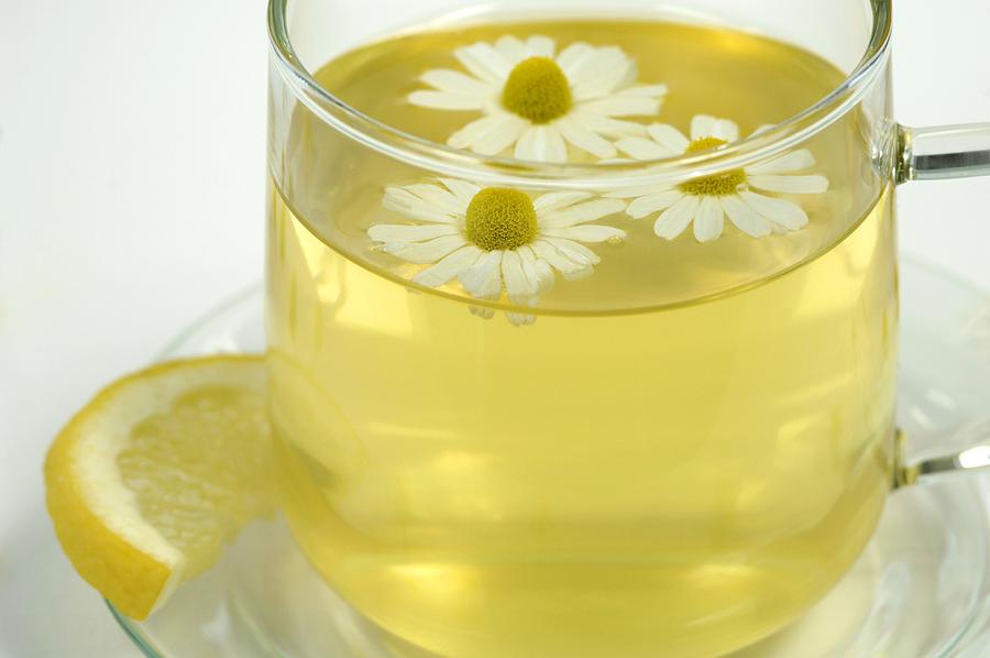 Chamomile tea in cup with flowers and lemon, close-up Photograph by Westend61 - WEP