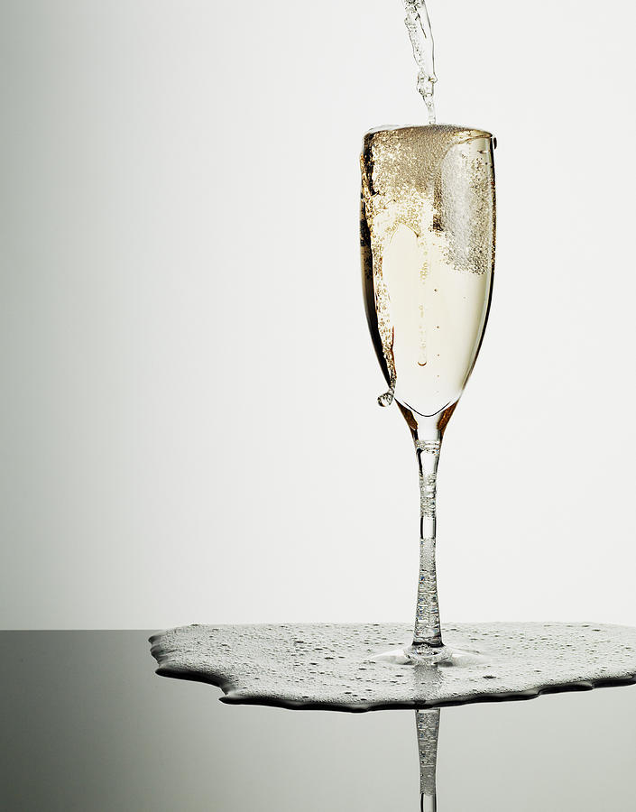 Champagne pouring into glass and overflowing Photograph by Martin Barraud