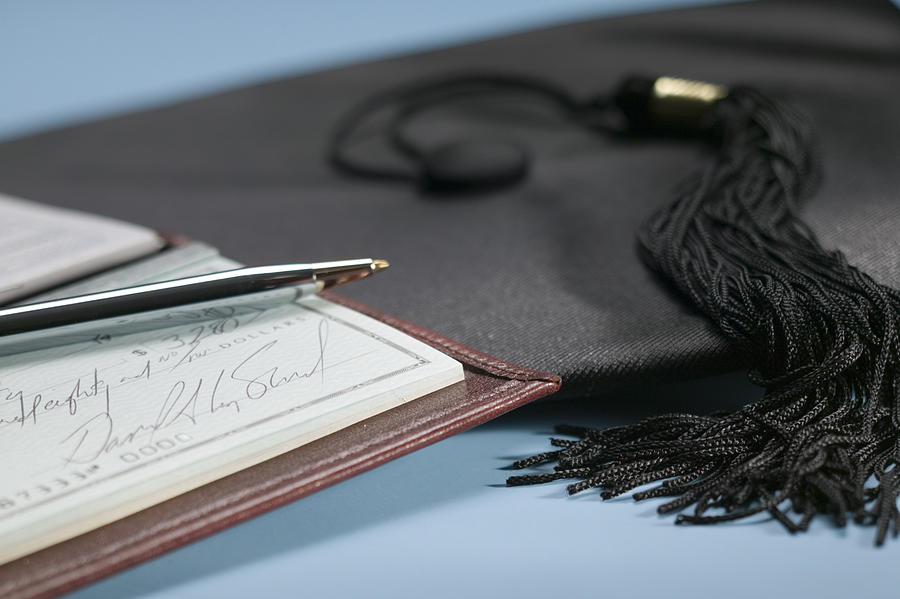 Checkbook and graduation cap Photograph by Comstock Images