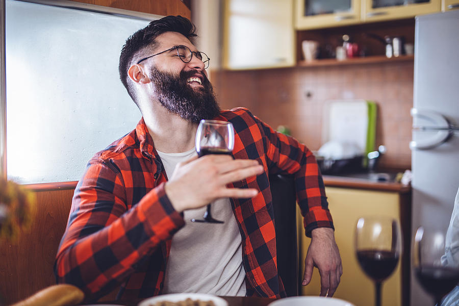 Cheerful bearded man in plaid shirt drinking wine Photograph by FluxFactory