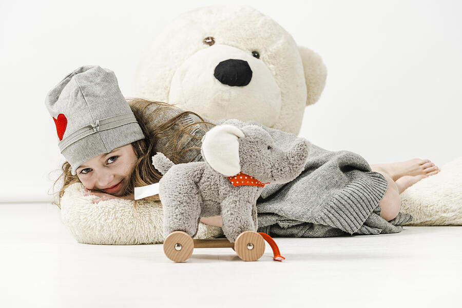 Cheerful girl is lying on huge teddy bear and hugs Photograph by Domin_domin