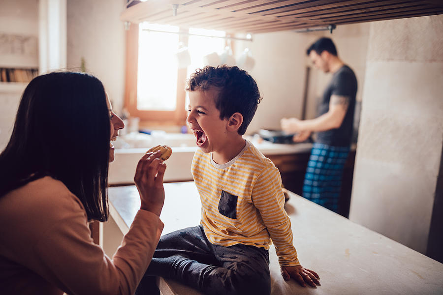 Cheerful mother giving little son cookie in the morning Photograph by Wundervisuals