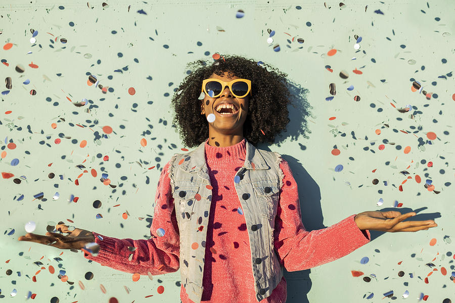 Cheerful woman with confetti enjoying in front of green wall Photograph by Westend61 Cheerful woman with confetti enjoying in front of green wall Photograph by Westend61