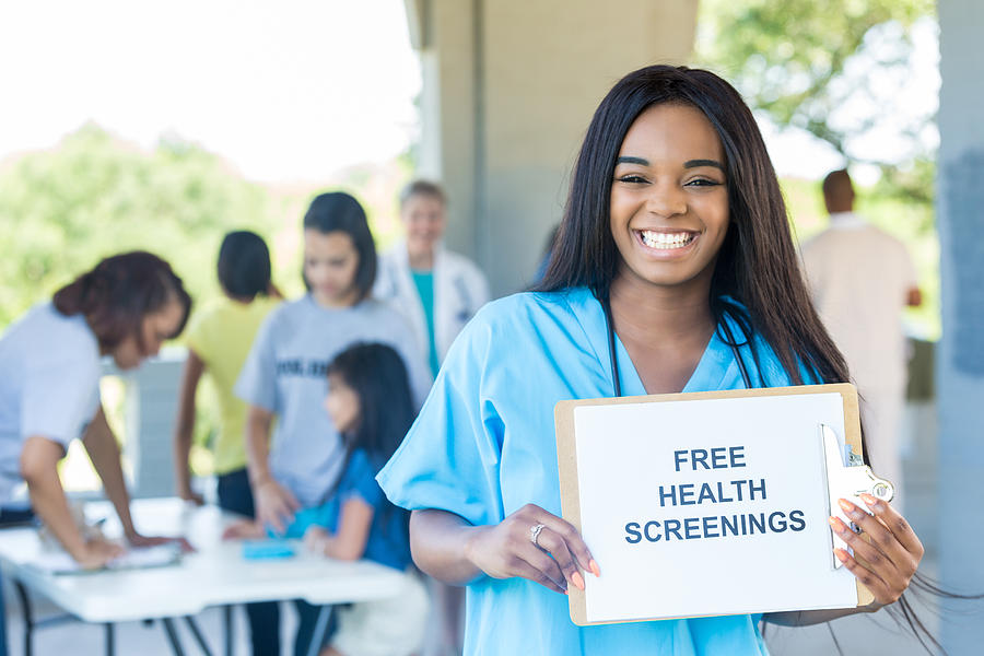 Cheerful young African American nurse promotes health fair Photograph by SDI Productions