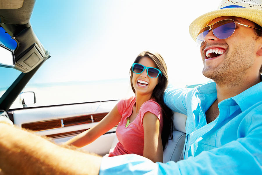 Cheerful young couple in a convertible car going for vacation Photograph by GlobalStock